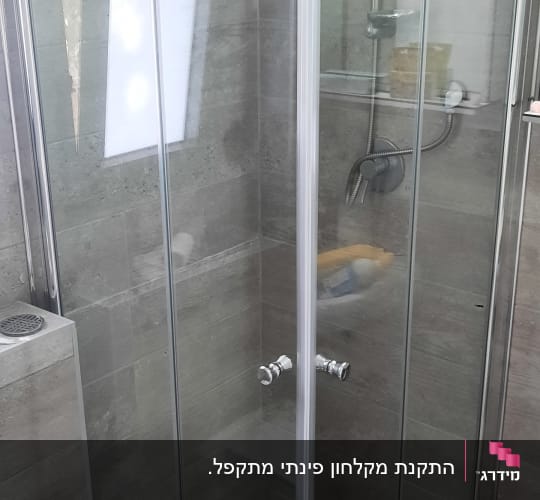 מקלחון פינתי מתקפל מזכוכית שקופה המותקן בחדר רחצה